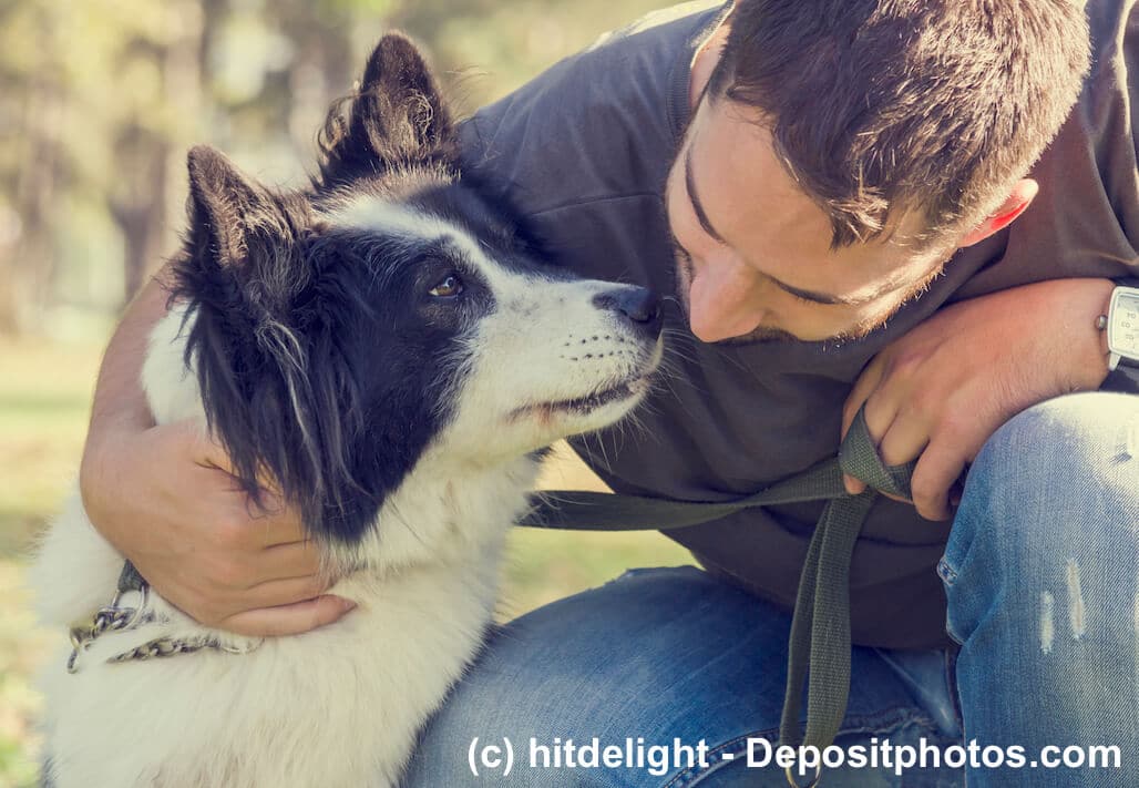 Ein Mann hockt neben seinem Hund und umarmt ihn, dieser schnüffelt an dessen Gesicht